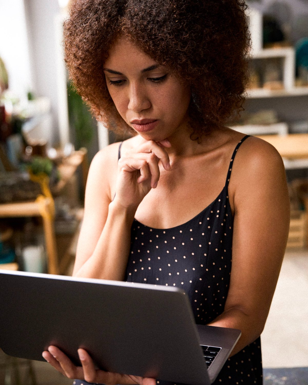 A creator standing in her studio, reviewing her laptop